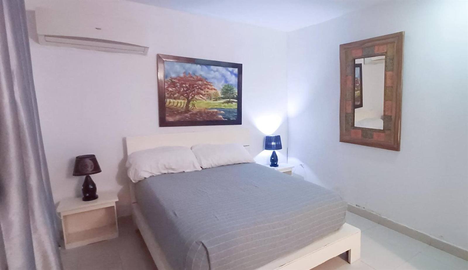 Gato Colonial: double room with grey bedding, wall art and a wooden mirror